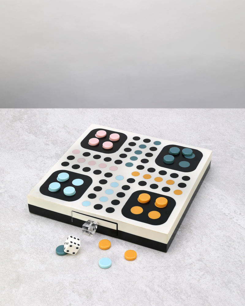 White Ludo game board with coloured home squares, counters and dice beside it