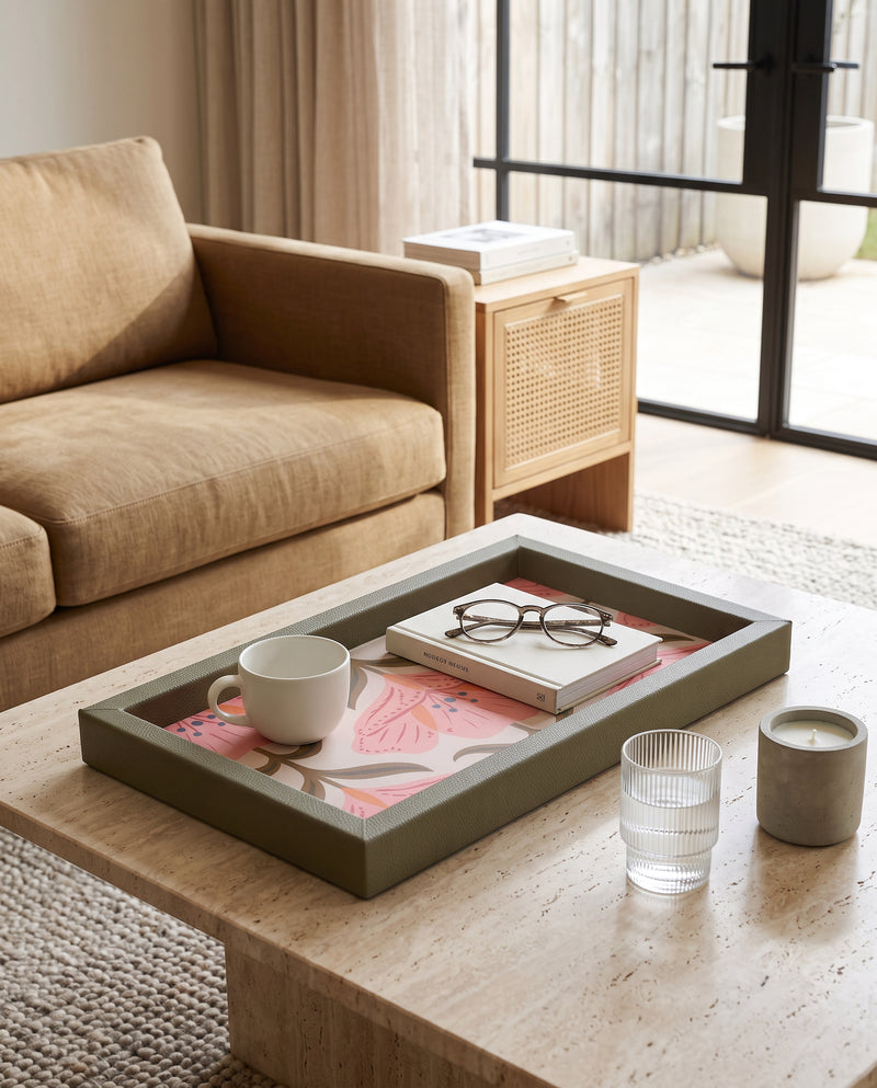 Green floral rectangular tray on an ottoman holding cups, glasses and a book