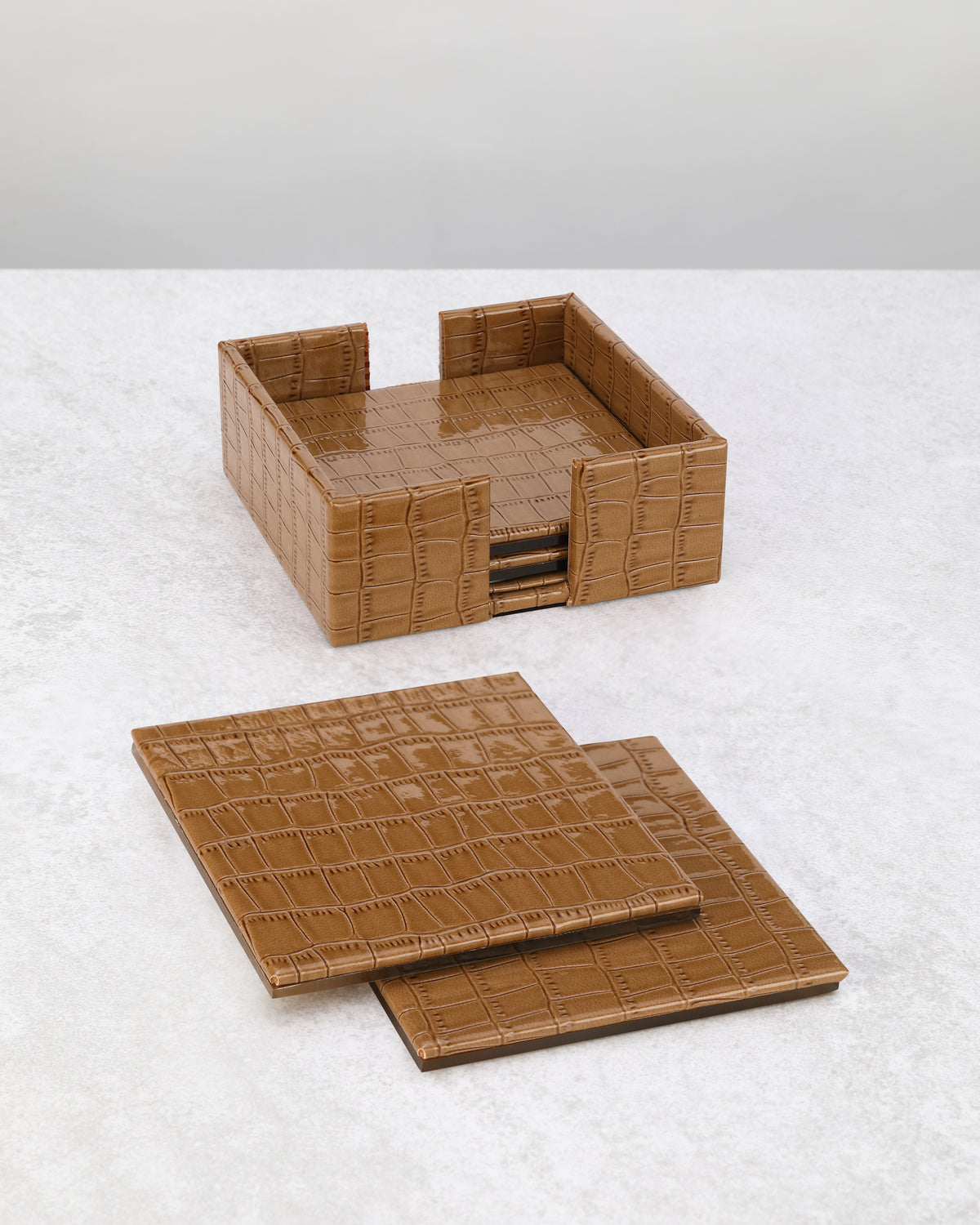 Beige faux leather coasters laid out beside their square holder