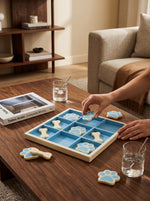 Blue resin tic-tac-toe board with bone and paw pieces being played on a coffee table