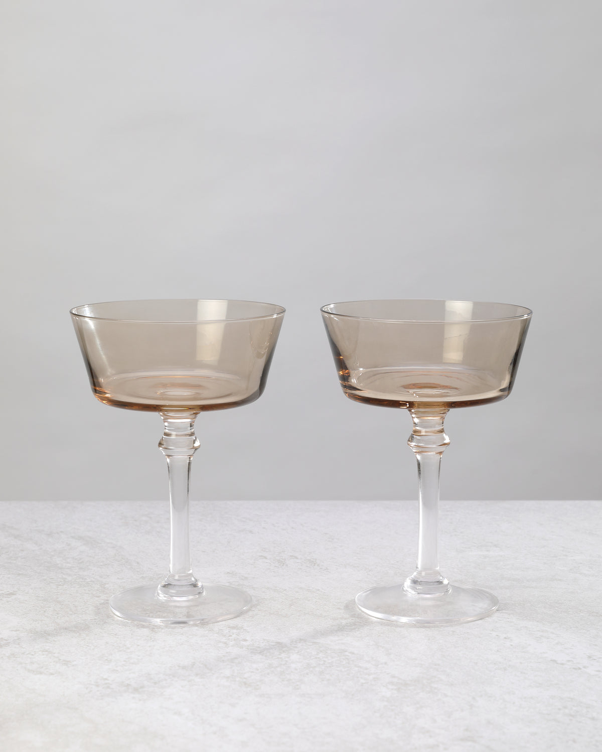 Pair of smoky coffee-tinted cocktail coupes on a white background