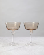 Pair of smoky coffee-tinted cocktail coupes on a white background