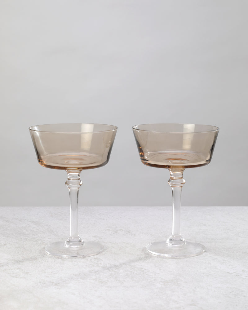 Pair of smoky coffee-tinted cocktail coupes on a white background