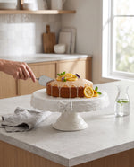 Lemon cake on the white glazed ceramic cake stand in a kitchen