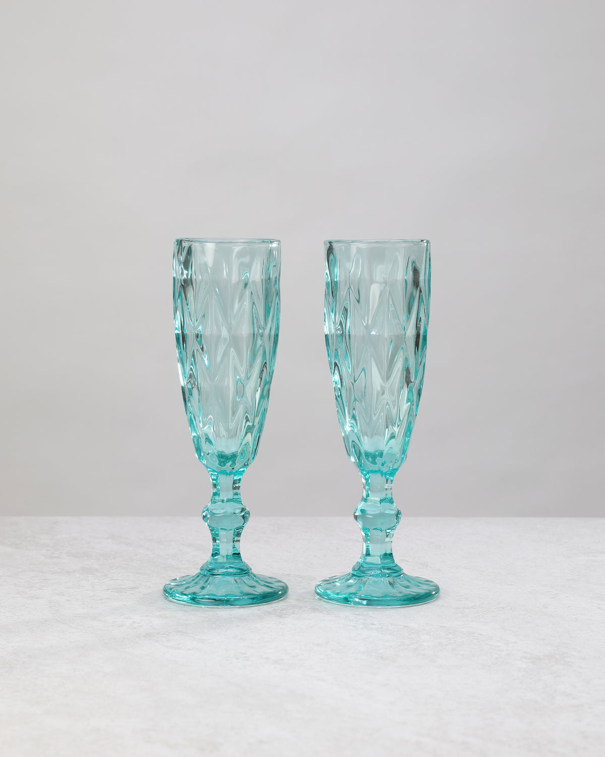 Pair of aqua diamond-cut champagne flutes on a white background