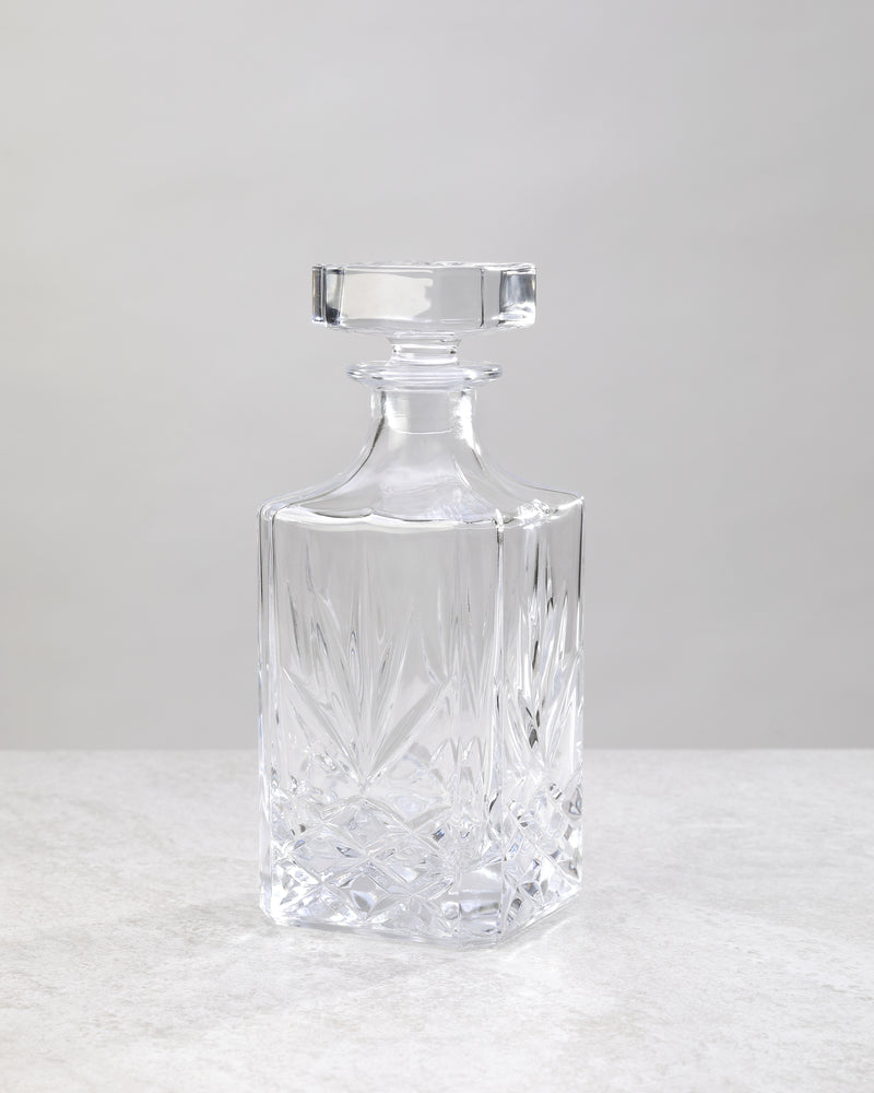 Clear machine cut glass decanter with a square stopper, on white