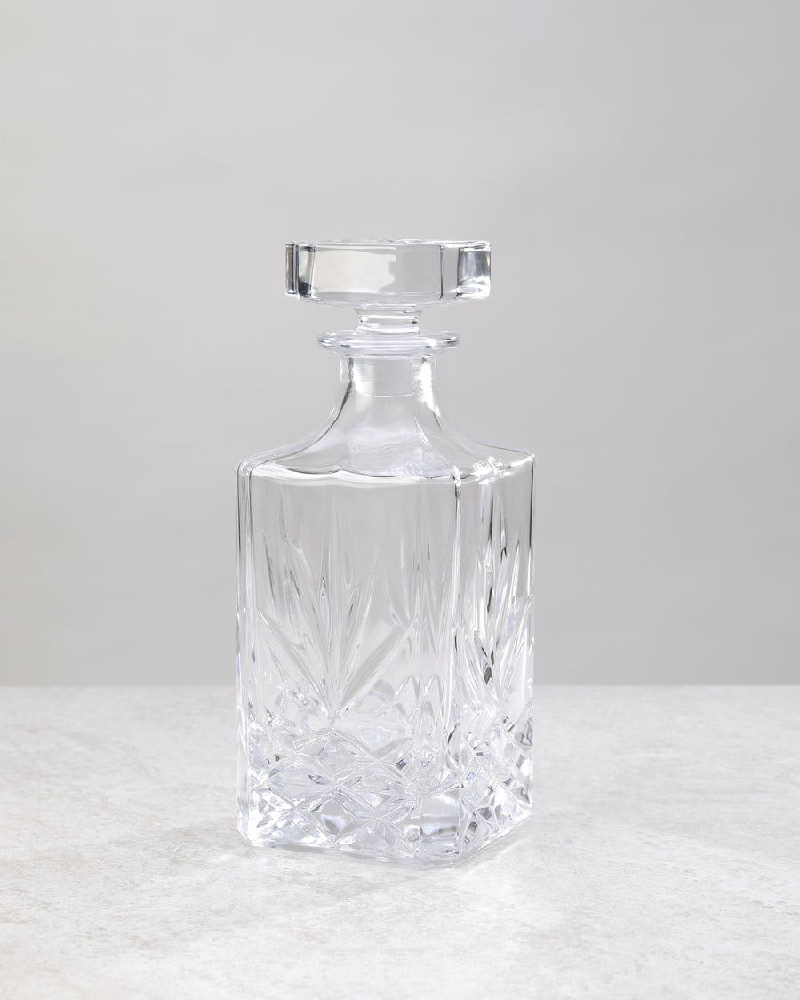 Clear machine cut glass decanter with a square stopper, on white