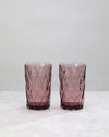 Two tall pink diamond cut highball glasses, on white