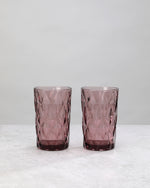 Two tall pink diamond cut highball glasses, on white