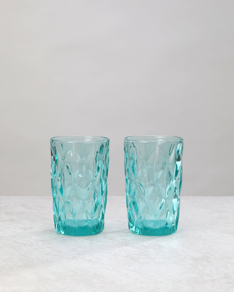 Two aqua diamond cut highball glasses with a large faceted pattern, on white