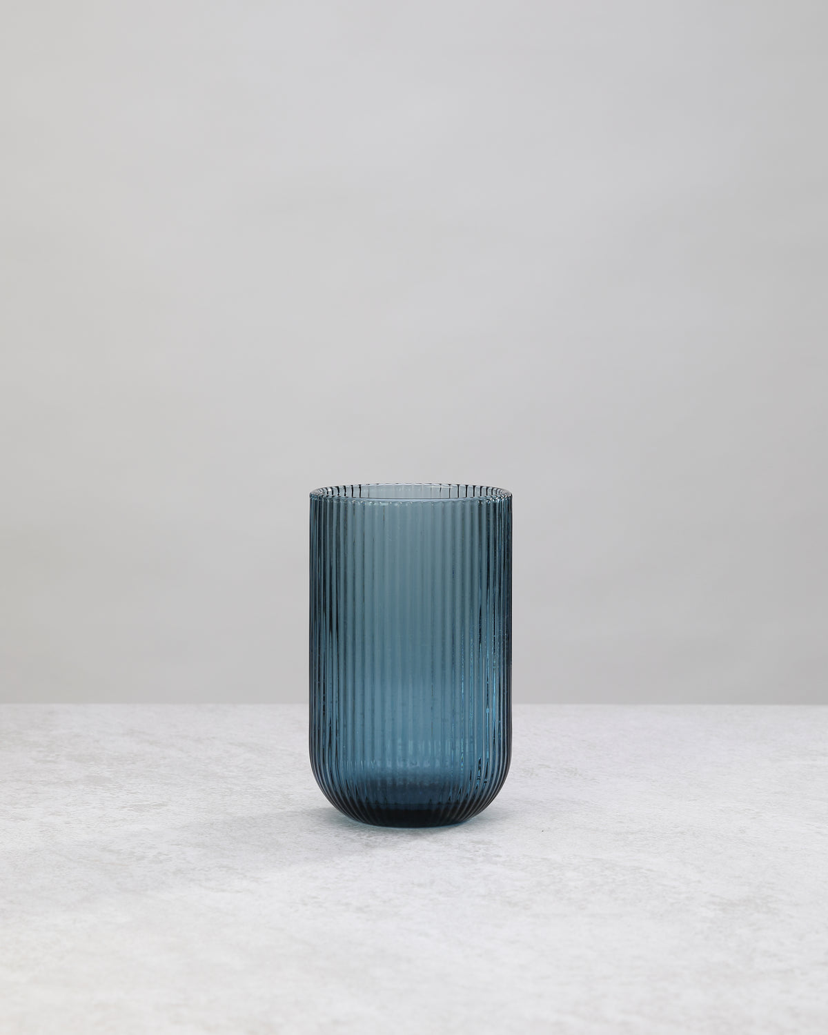 Single tall blue ribbed highball glass, front view