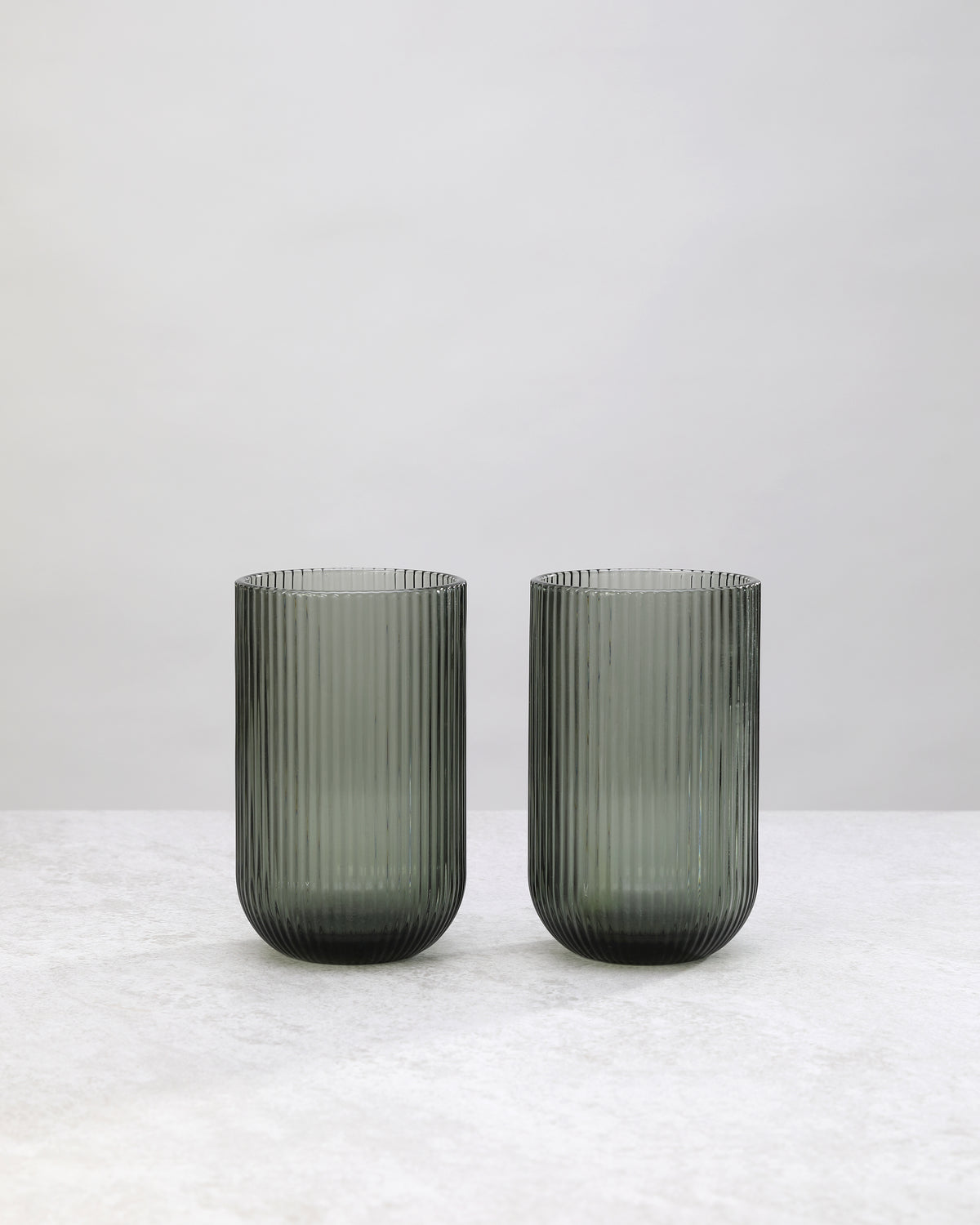 Pair of hunter green ribbed high ball glasses on a white background