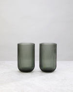 Pair of hunter green ribbed high ball glasses on a white background