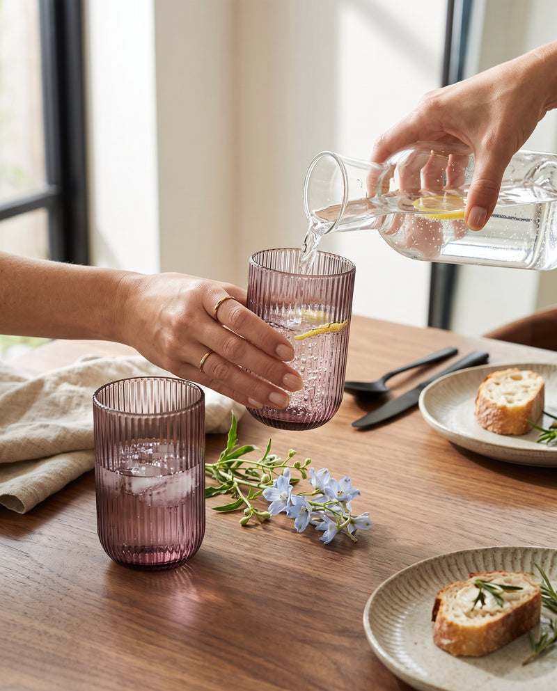 Water being poured into cordovan ribbed highball glasses at a lunch table
