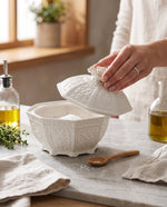 Hand lifting the lid of the white porcelain jar on a kitchen counter