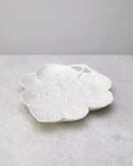 White glazed porcelain leaf-shaped plate with an embossed pattern, on white