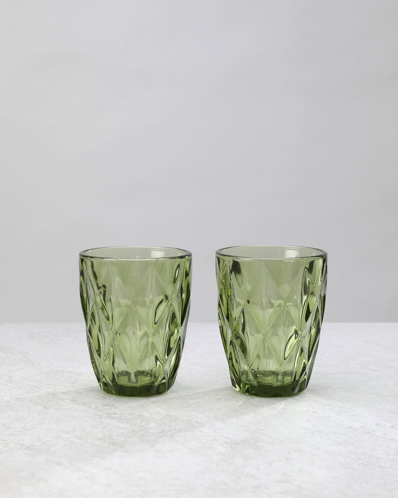Two olive green diamond cut tumbler glasses with a large faceted pattern, on white