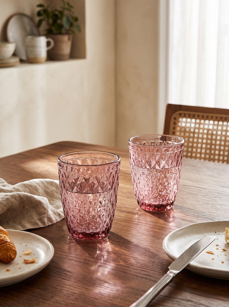 Pink diamond tumblers on a wooden dining table set for lunch