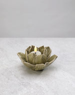 Sage green ceramic lotus tea light holder with a lit candle