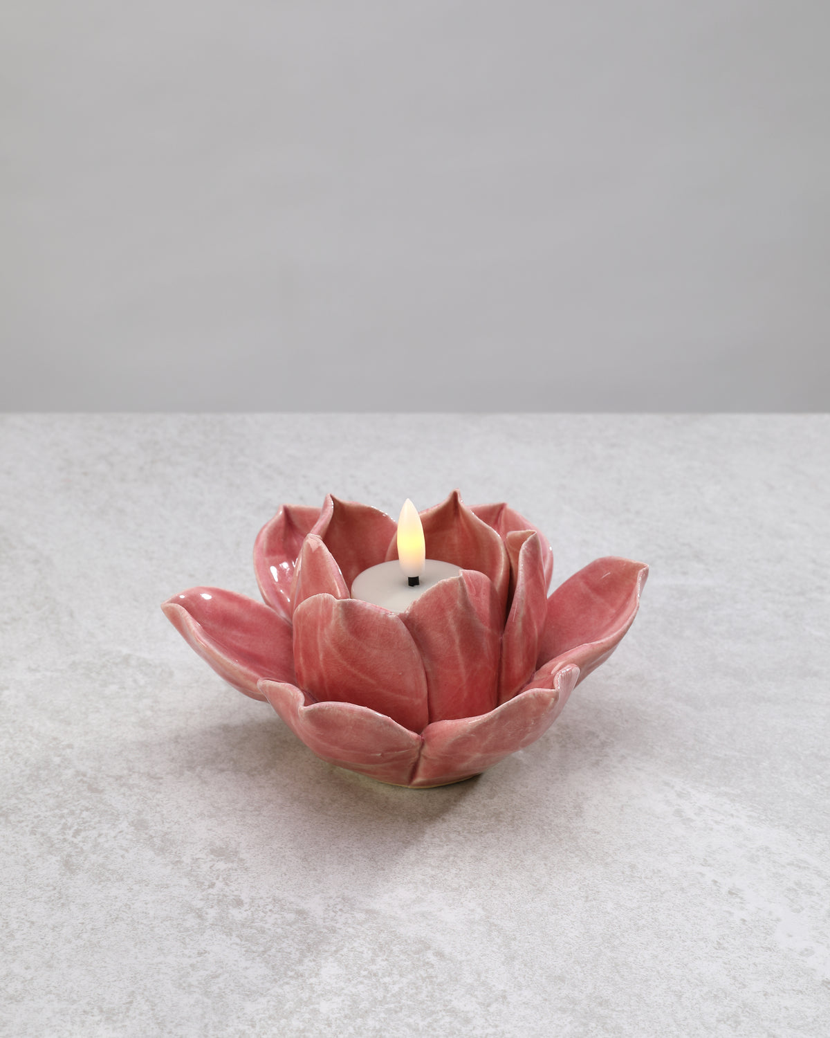 Pink ceramic lotus tea light holder with a lit candle