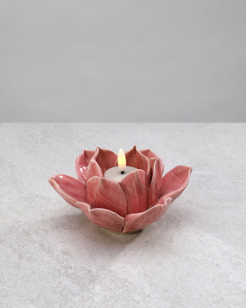 Pink ceramic lotus tea light holder with a lit candle
