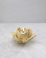 Soft gold ceramic lotus tea light holder with a lit candle