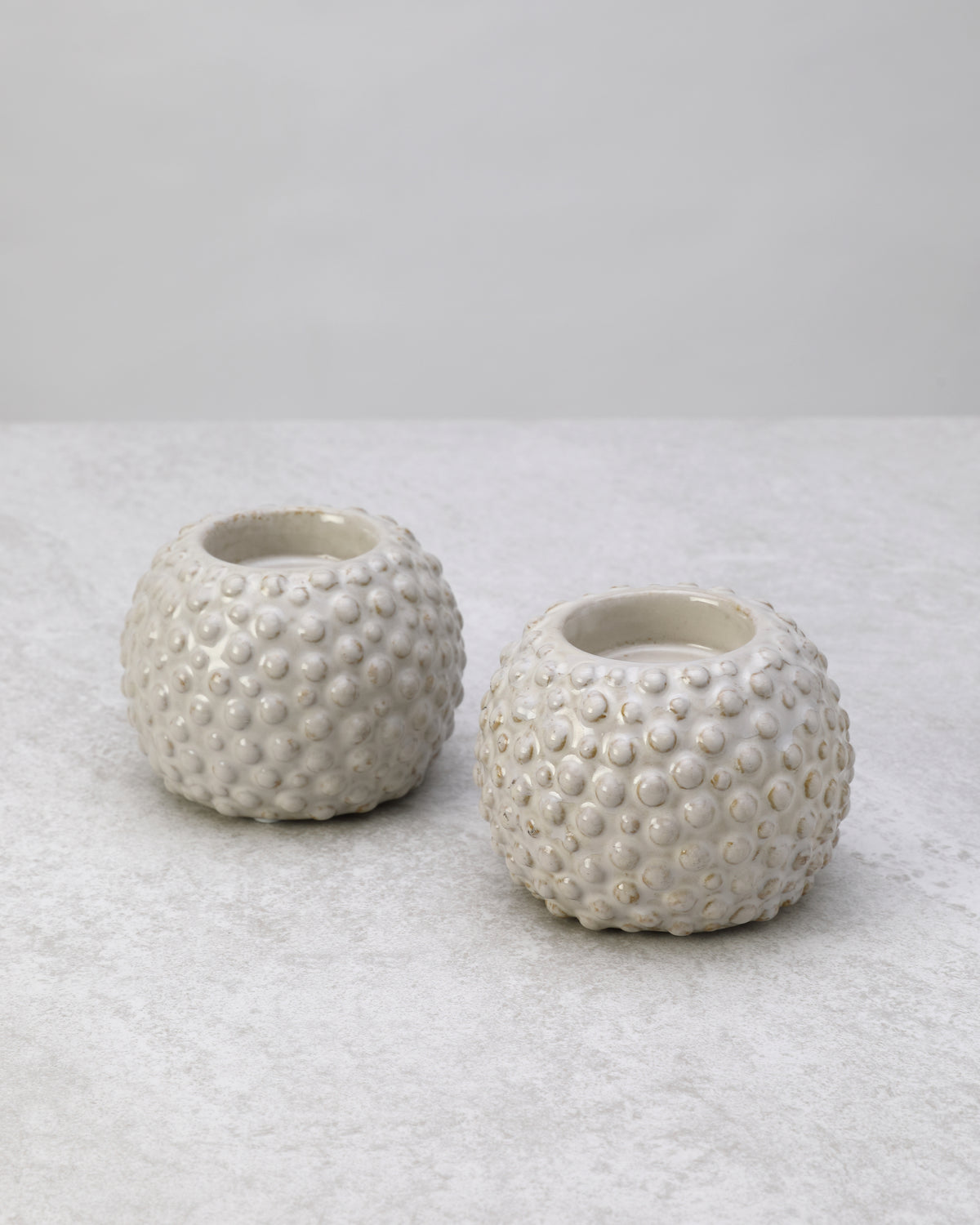 Pair of white textured ceramic tea light holders, unlit