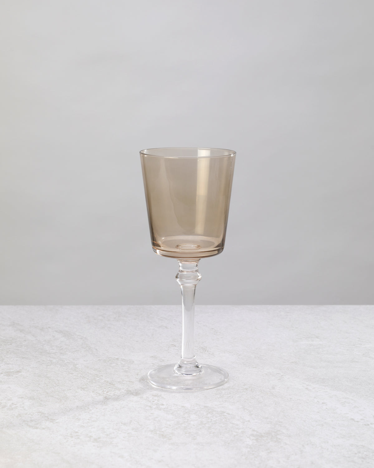 Single coffee-brown wine glass on a clear stem, front view