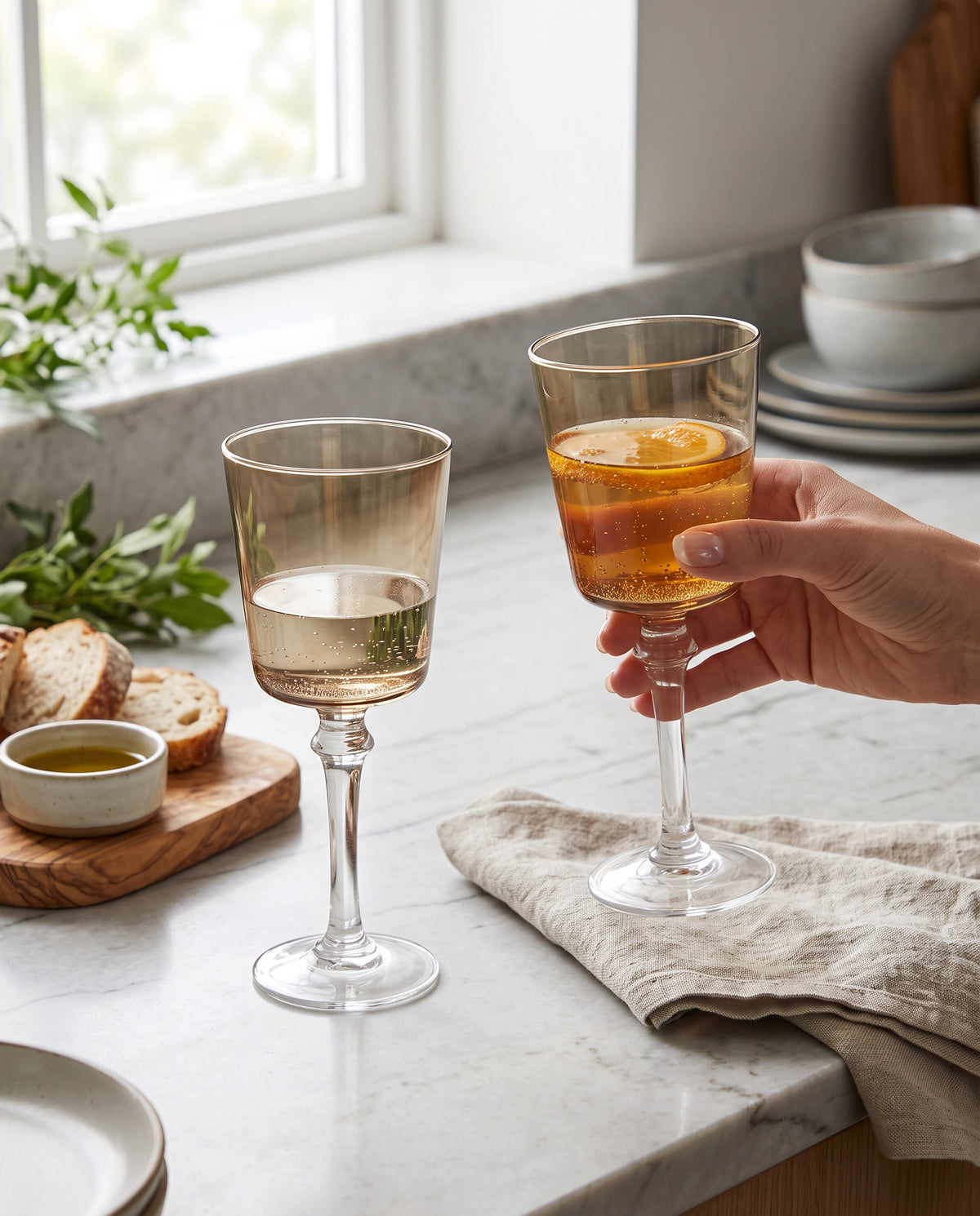 Coffee-brown wine glasses being raised at a kitchen counter set with small plates