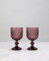 Pair of burgundy ribbed cut wine glasses on a white background