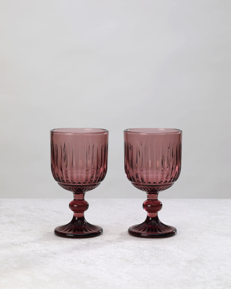 Pair of burgundy ribbed cut wine glasses on a white background