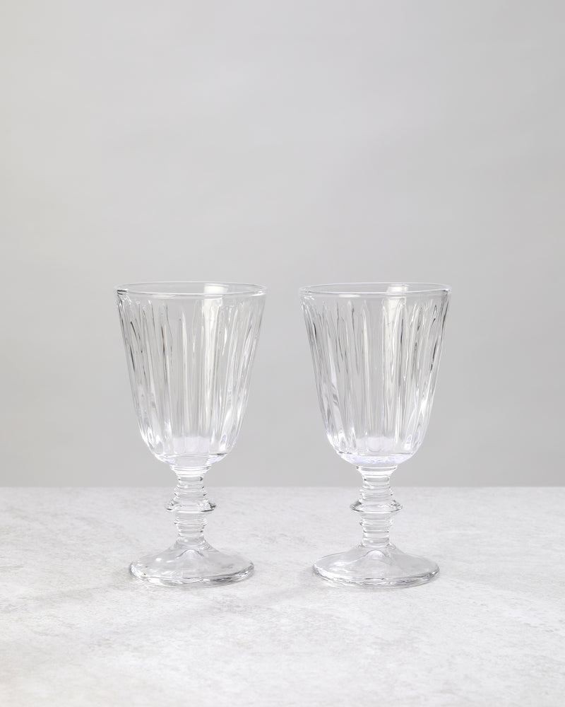 Two clear full ribbed wine glasses on knotted stems, on white