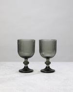 Pair of hunter green ribbed wine glasses on a white background