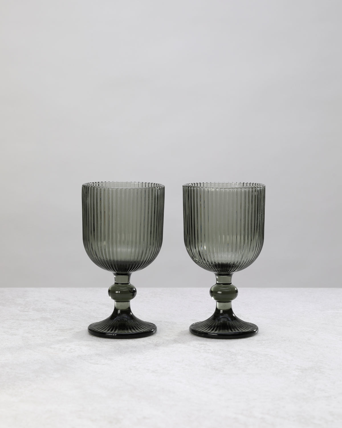 Pair of hunter green ribbed wine glasses on a white background