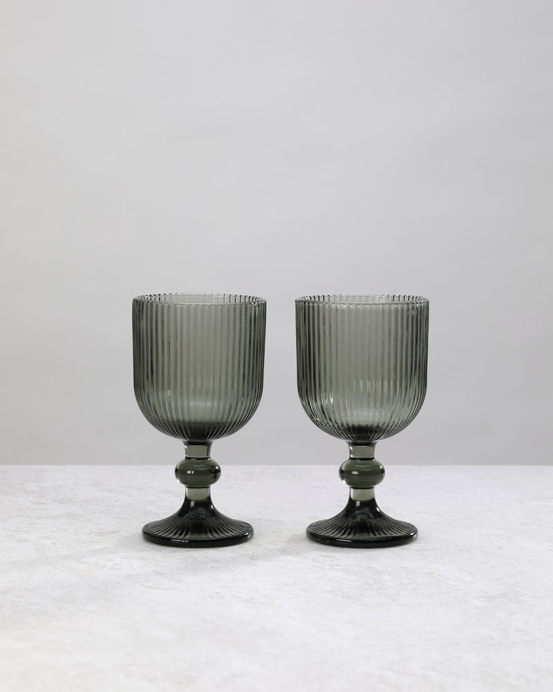 Pair of hunter green ribbed wine glasses on a white background