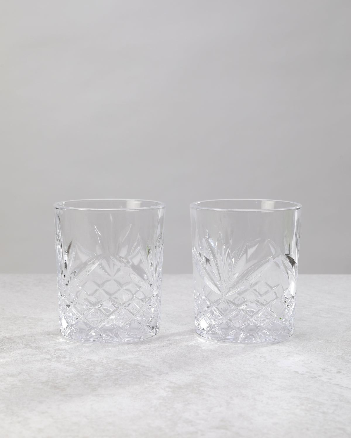 Pair of clear machine cut whiskey glasses on a white background
