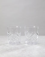 Pair of clear machine cut whiskey glasses on a white background