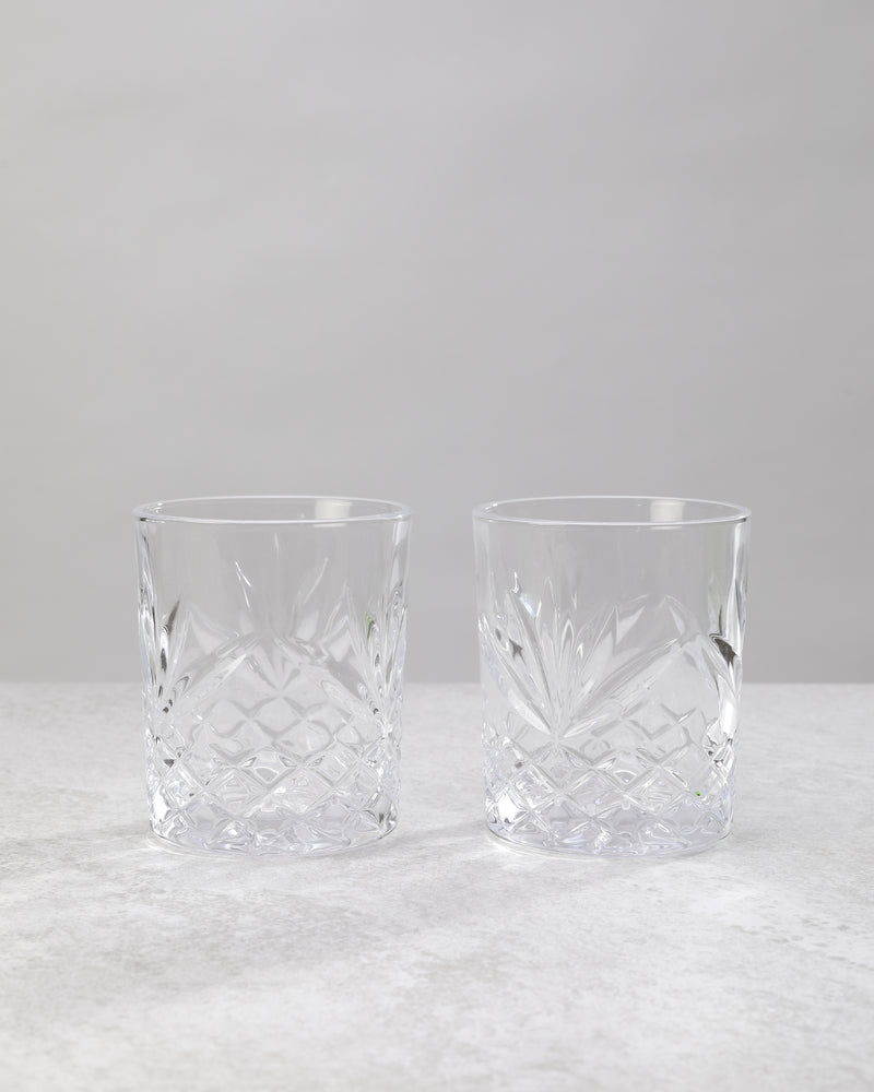 Pair of clear machine cut whiskey glasses on a white background