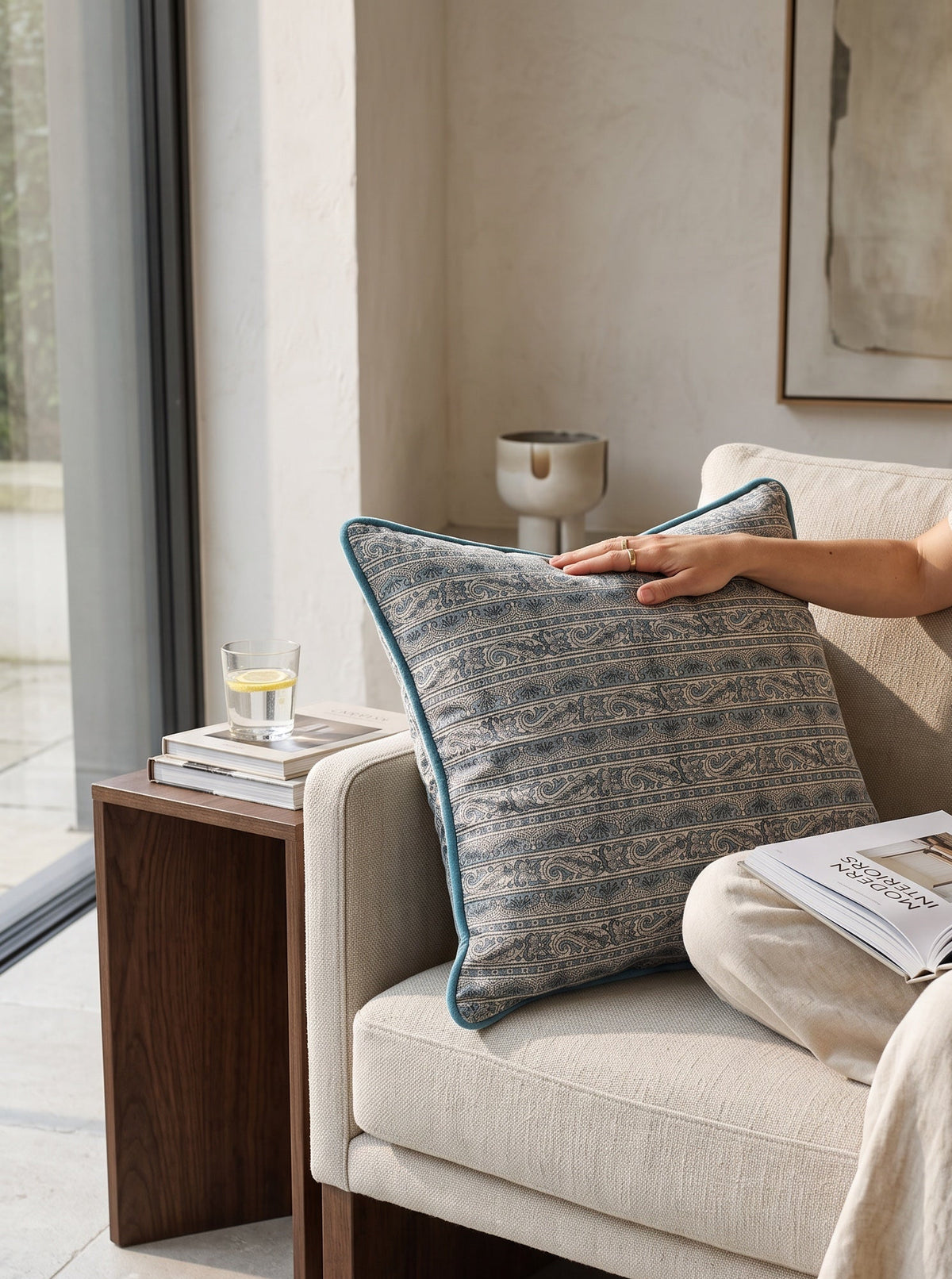 Blue piped printed cushion on an armchair, a hand resting on it