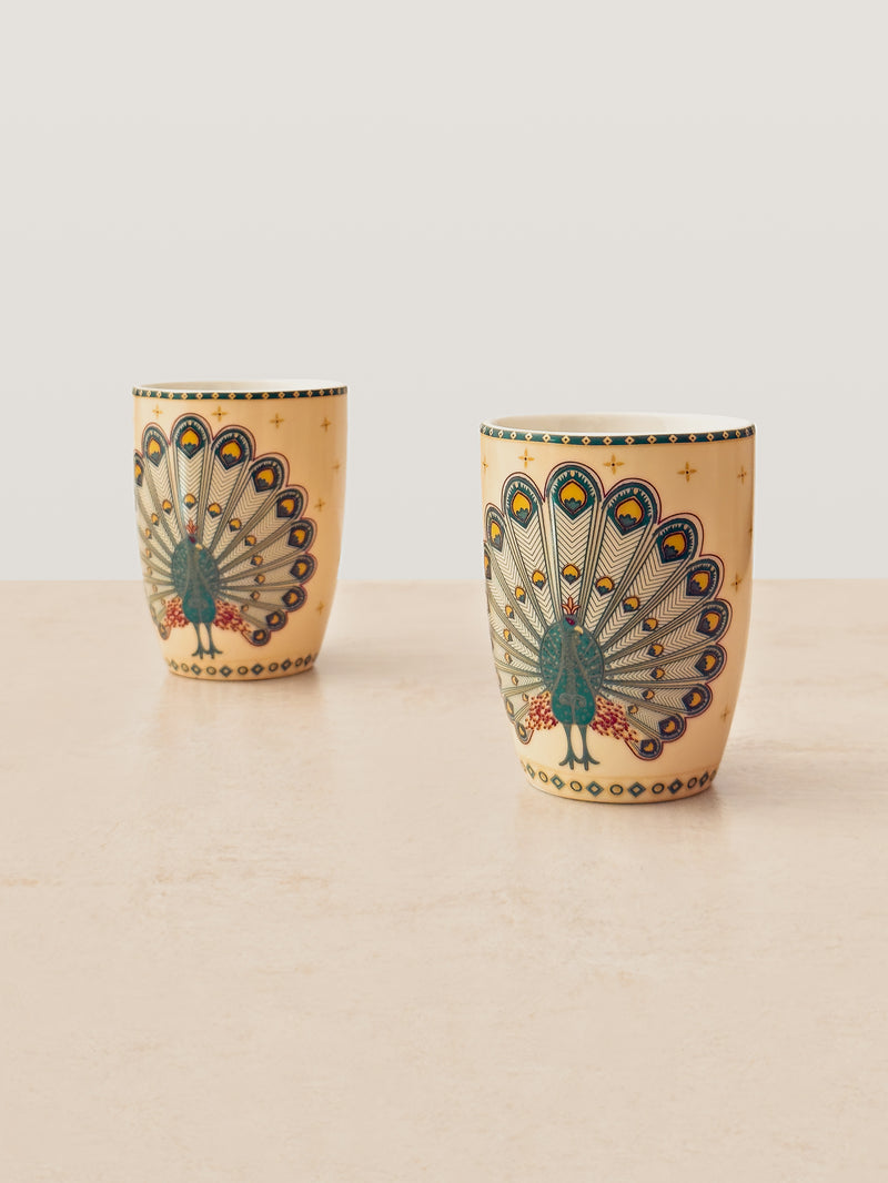 Two tall Mor Bagh porcelain coffee mugs in Dusk with a dark green peacock print, front view