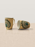 Mor Bagh Dusk coffee mugs, one standing and one lying on its side, peacock print in view