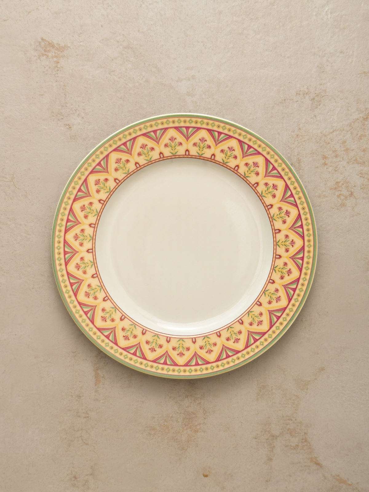Mor Bagh Dawn dinner plate from above, showing the pink and gold border on a stone background
