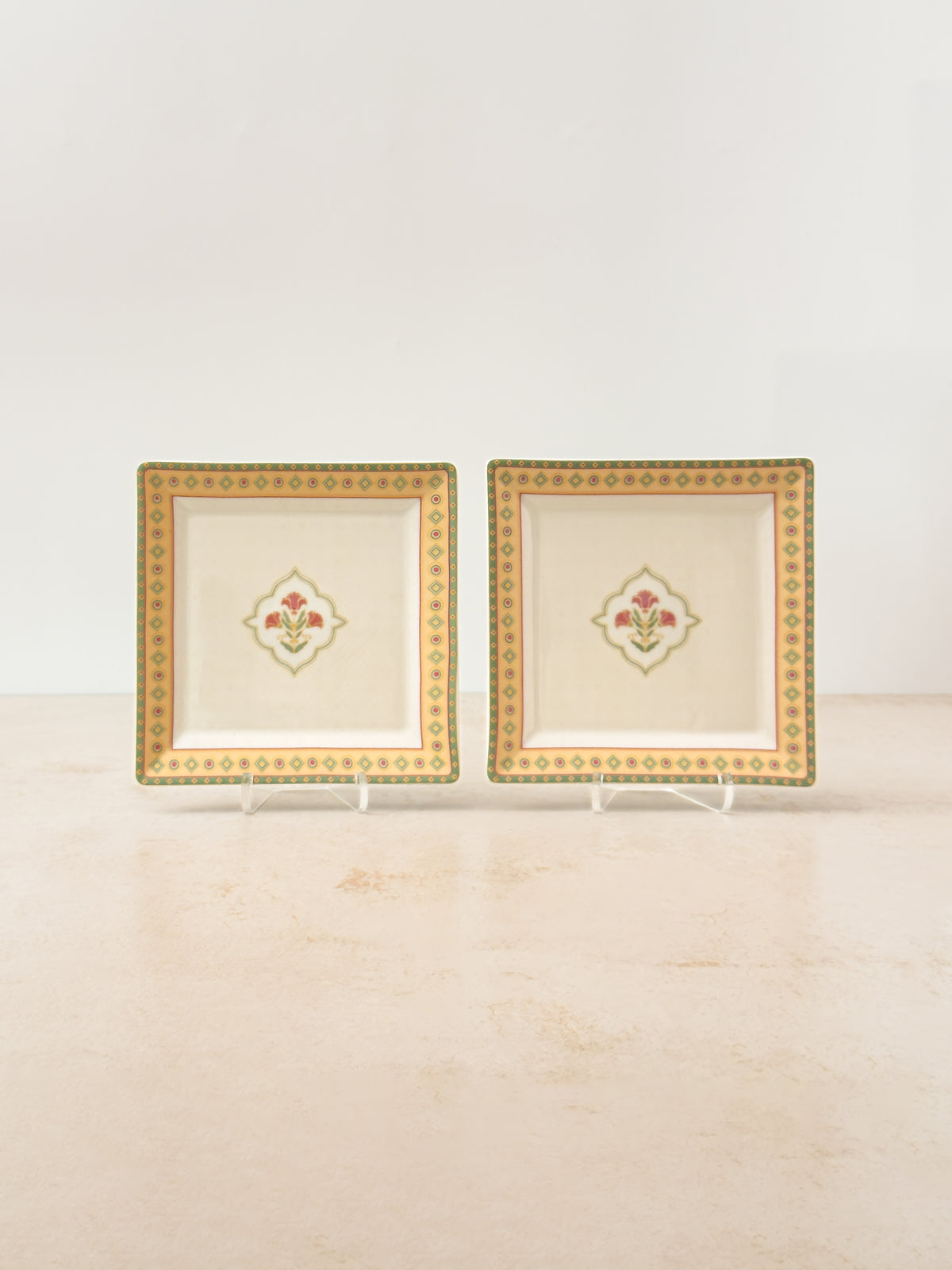 Two Mor Bagh Dawn porcelain square platters on stands, gold border and a small centre motif