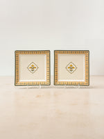 Two Mor Bagh Dusk porcelain square platters on stands with a gold border and centre motif