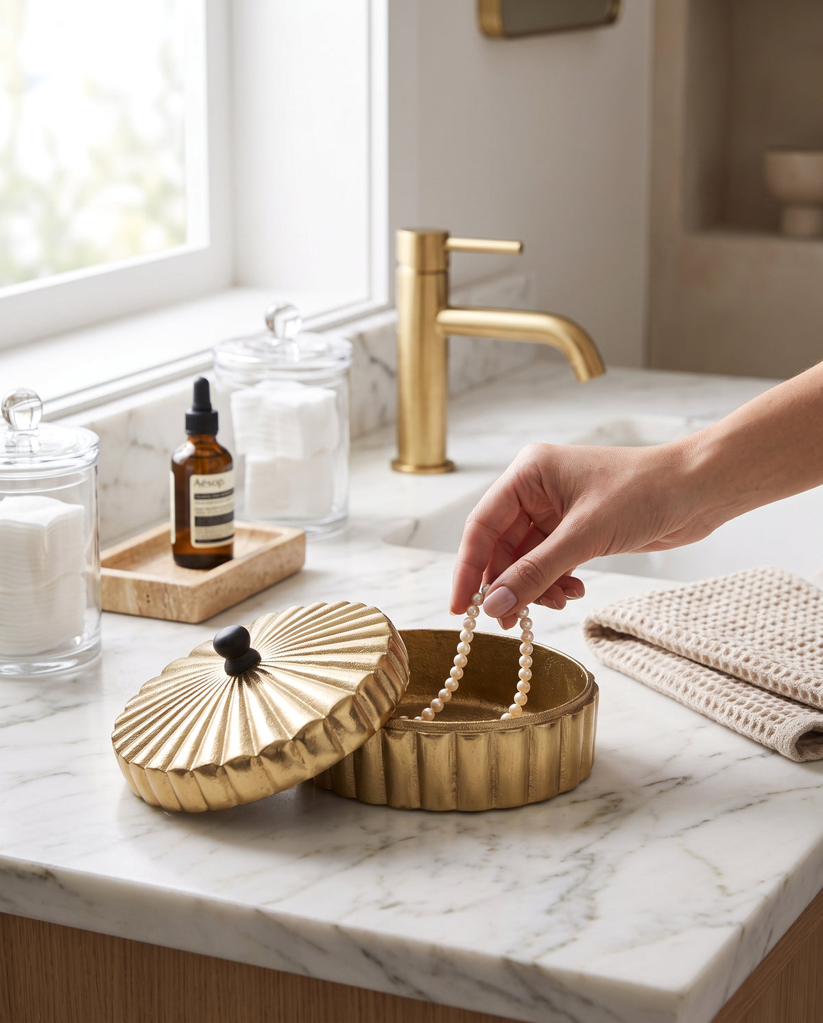 Large gold keepsake box on a bathroom counter, a hand lifting cotton from inside