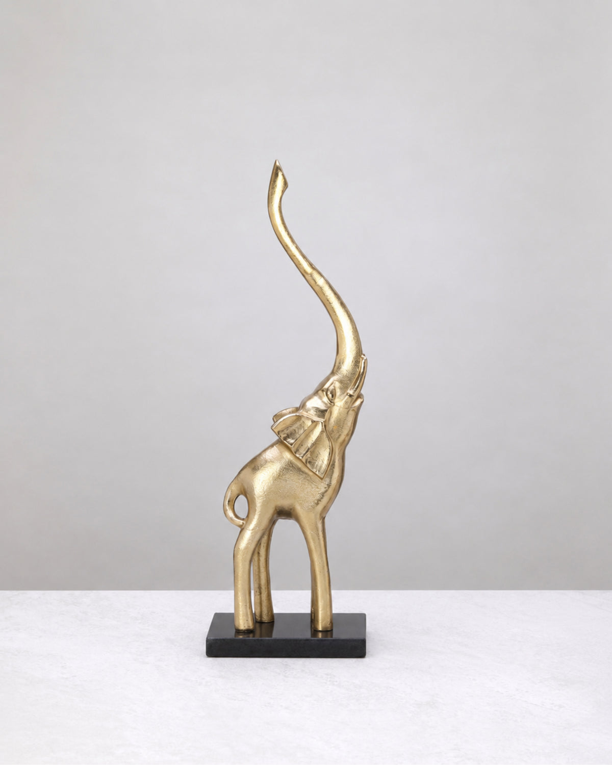 Grand gold elephant with raised trunk on a marble base