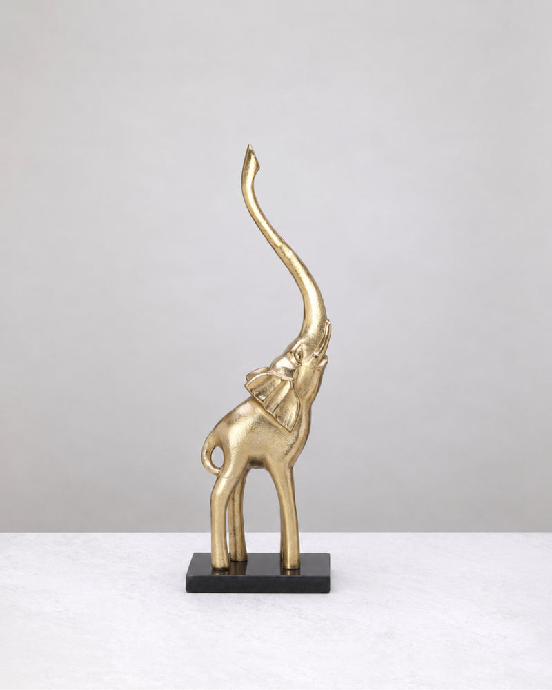 Grand gold elephant with raised trunk on a marble base