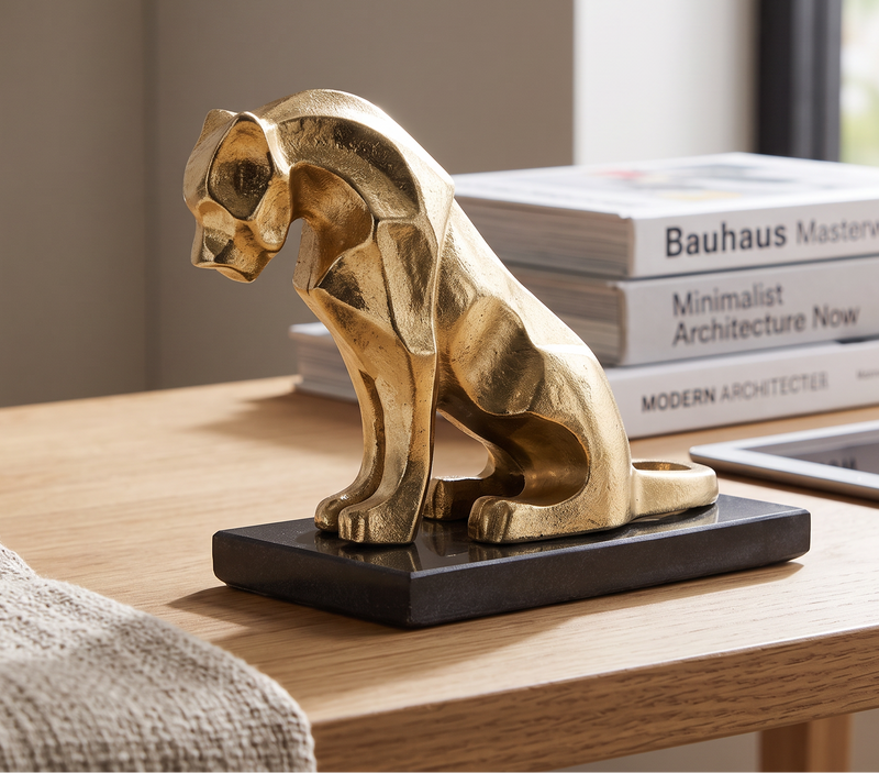 Gold lion figure on a black marble base on a desk beside a stack of books