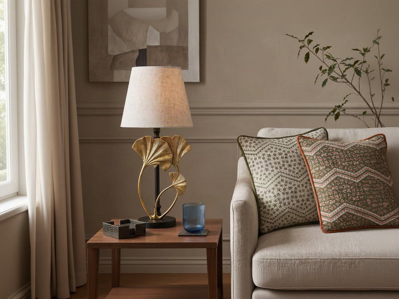 Gilded black silhouette lamp with a shade on a side table beside a sofa
