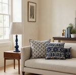 Blue Ari cushions with patterned cushions on a cream sofa beside a blue lamp